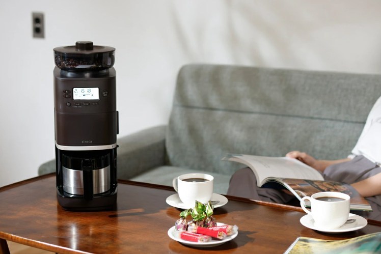 リビングのテーブルに置かれたシロカのコーヒーメーカーと2杯のコーヒー。くつろぎながら楽しむ様子。
