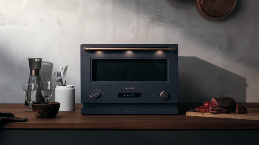 バルミューダ・ザ・レンジがキッチンカウンターに置かれている様子。温かみのある照明が上部のバーライトから照らされ、上質な空間を演出している。