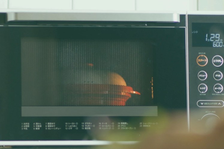 電子レンジの中でフタをしたレンジメートプロが加熱中。油ハネやにおいを防ぐ様子。
