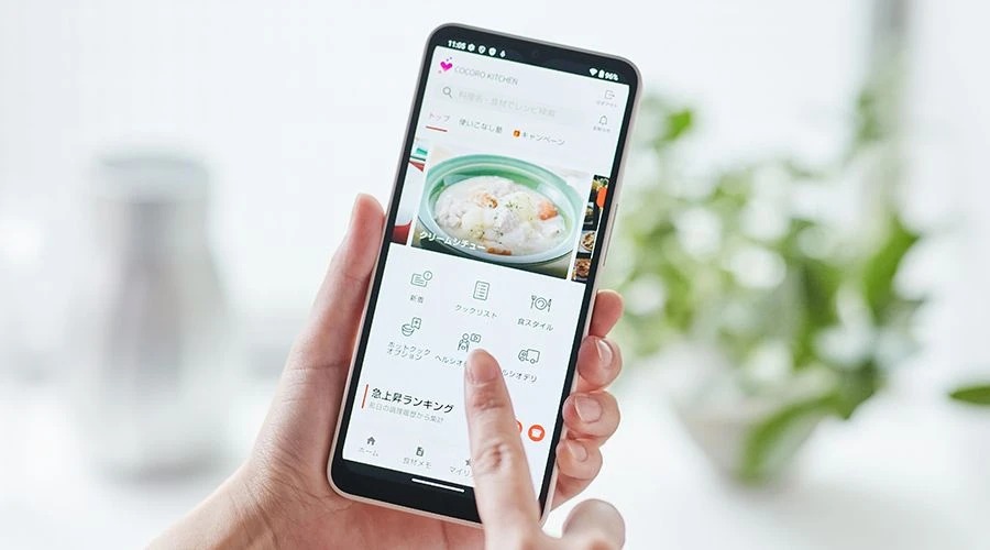 スマートフォンでCOCORO KITCHENアプリを操作している様子。レシピ検索やメニュー送信機能を利用できる画面。