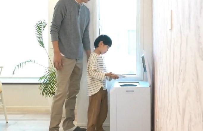 家の中で親子がナクスルに生ごみを入れている様子。高さのある本体を横から見たイメージ。