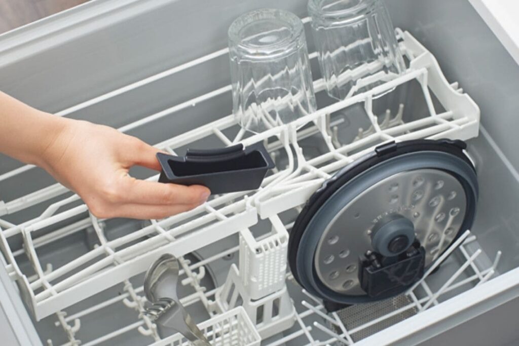 タイガー電気圧力鍋のつゆ受けと内ぶたを食洗機にセットする様子。油汚れが気になるパーツも手間なく洗浄可能