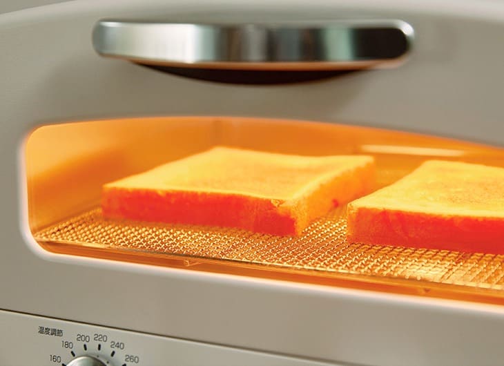 アラジントースターの遠赤グラファイトヒーターがオレンジ色に発光し食パン2枚を高温で焼いている庫内の様子